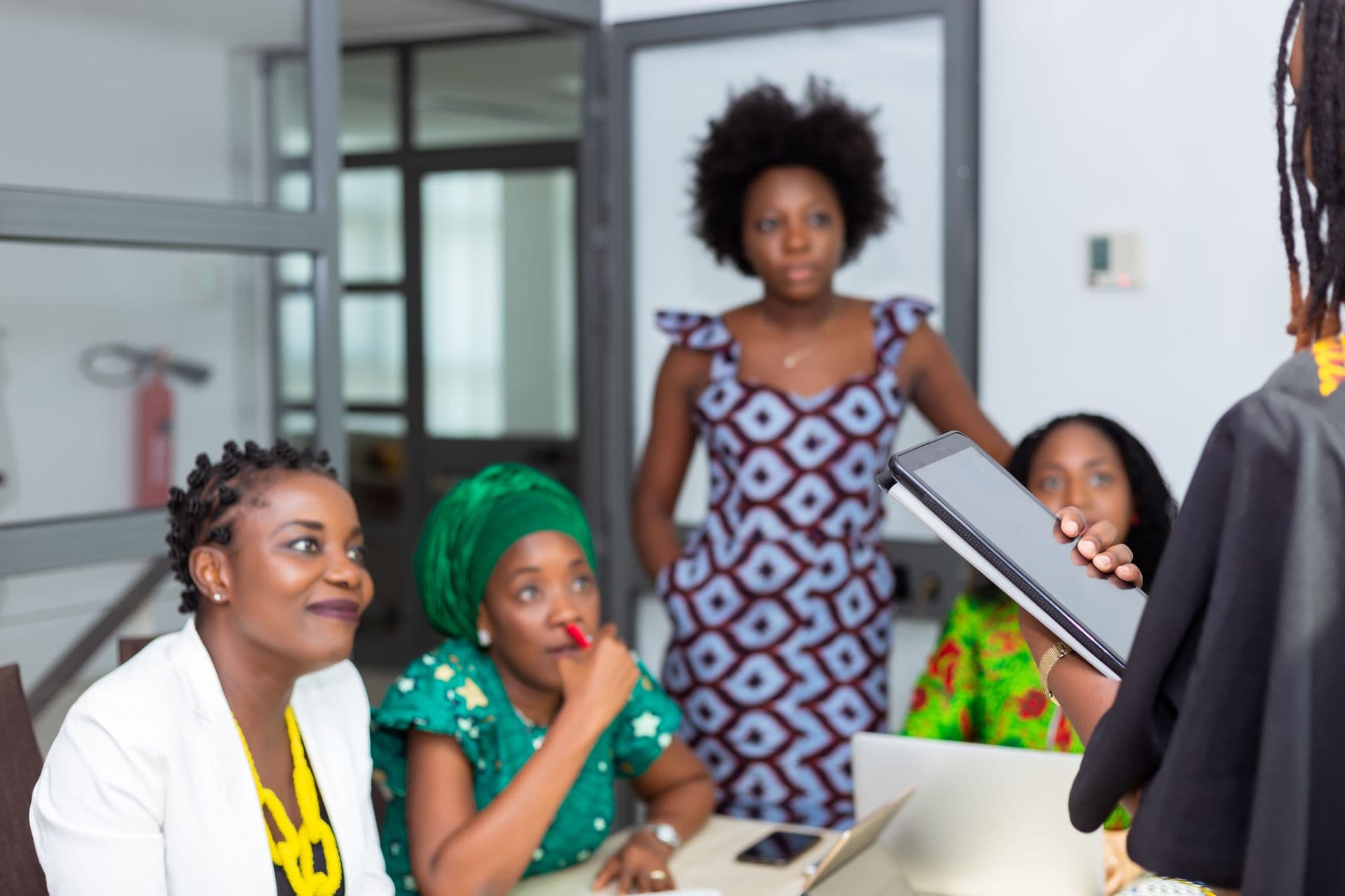 A group of women working together around a laptop in an office.